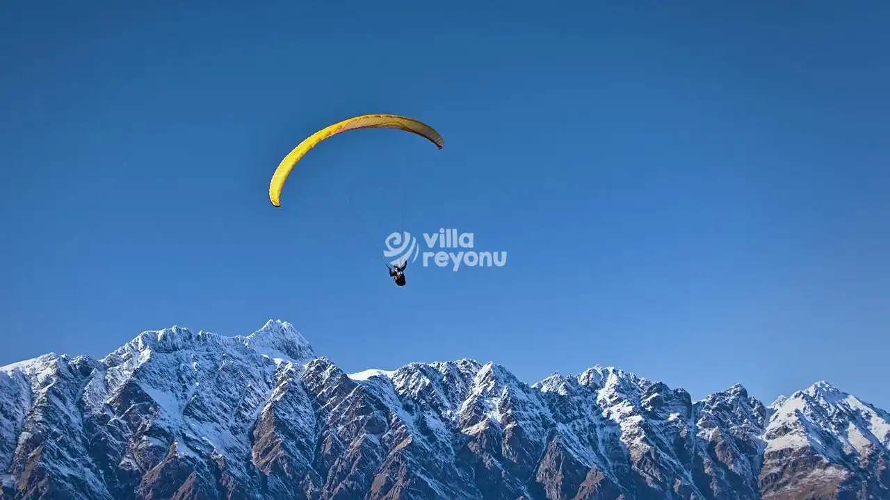 paraşütle atlyan bir adam ve kar manzarası